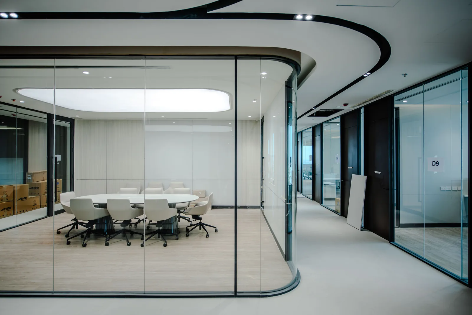 Glass walled meeting room off a curved office corridor