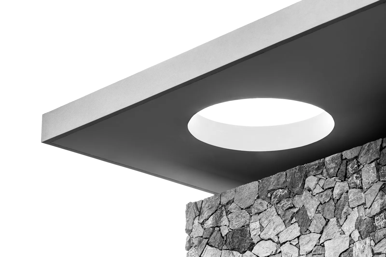 A square recessed ceiling fitting shown against a stone wall surface