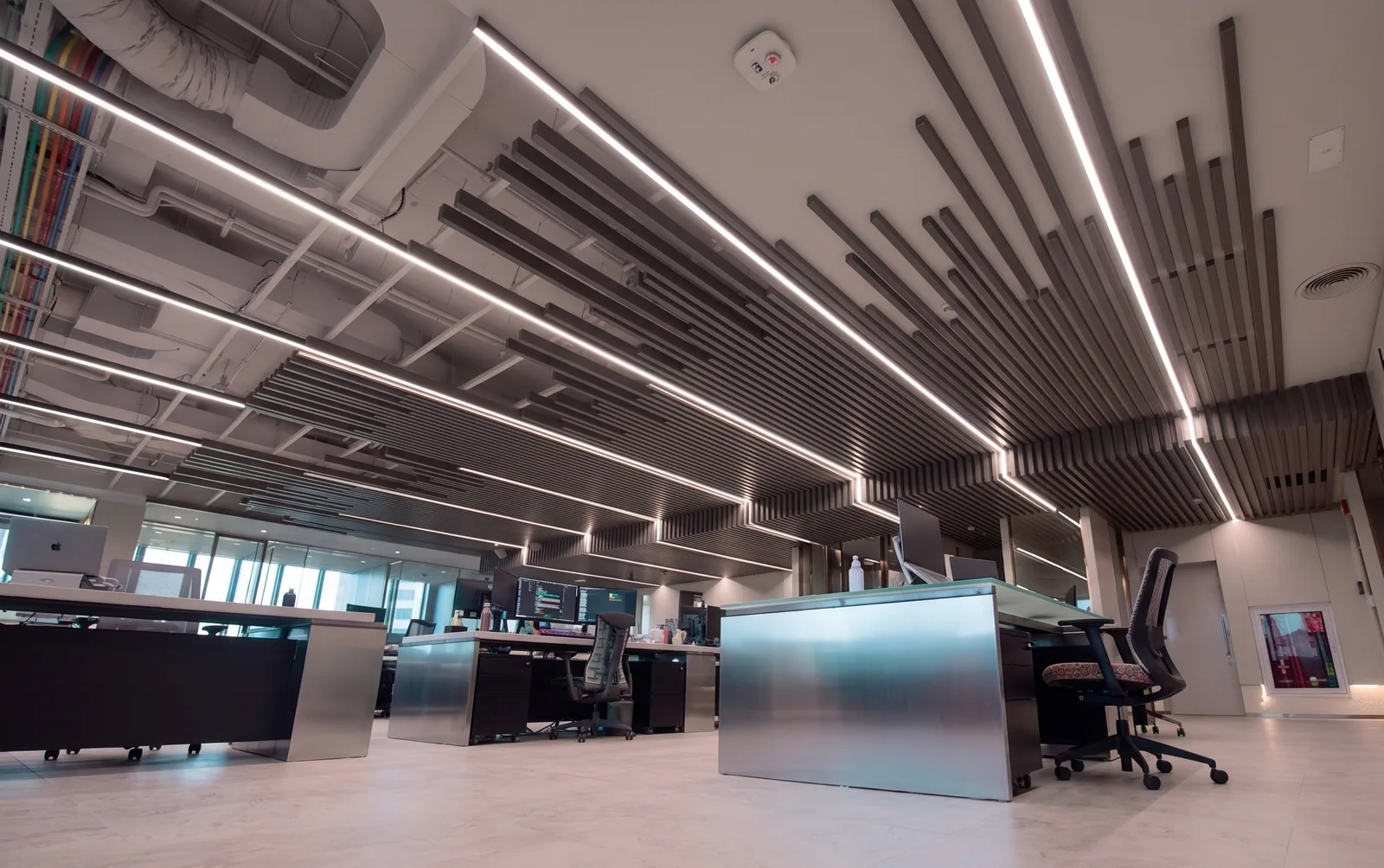 A completed open plan office floor with linear ceiling lighting and glazed meeting rooms