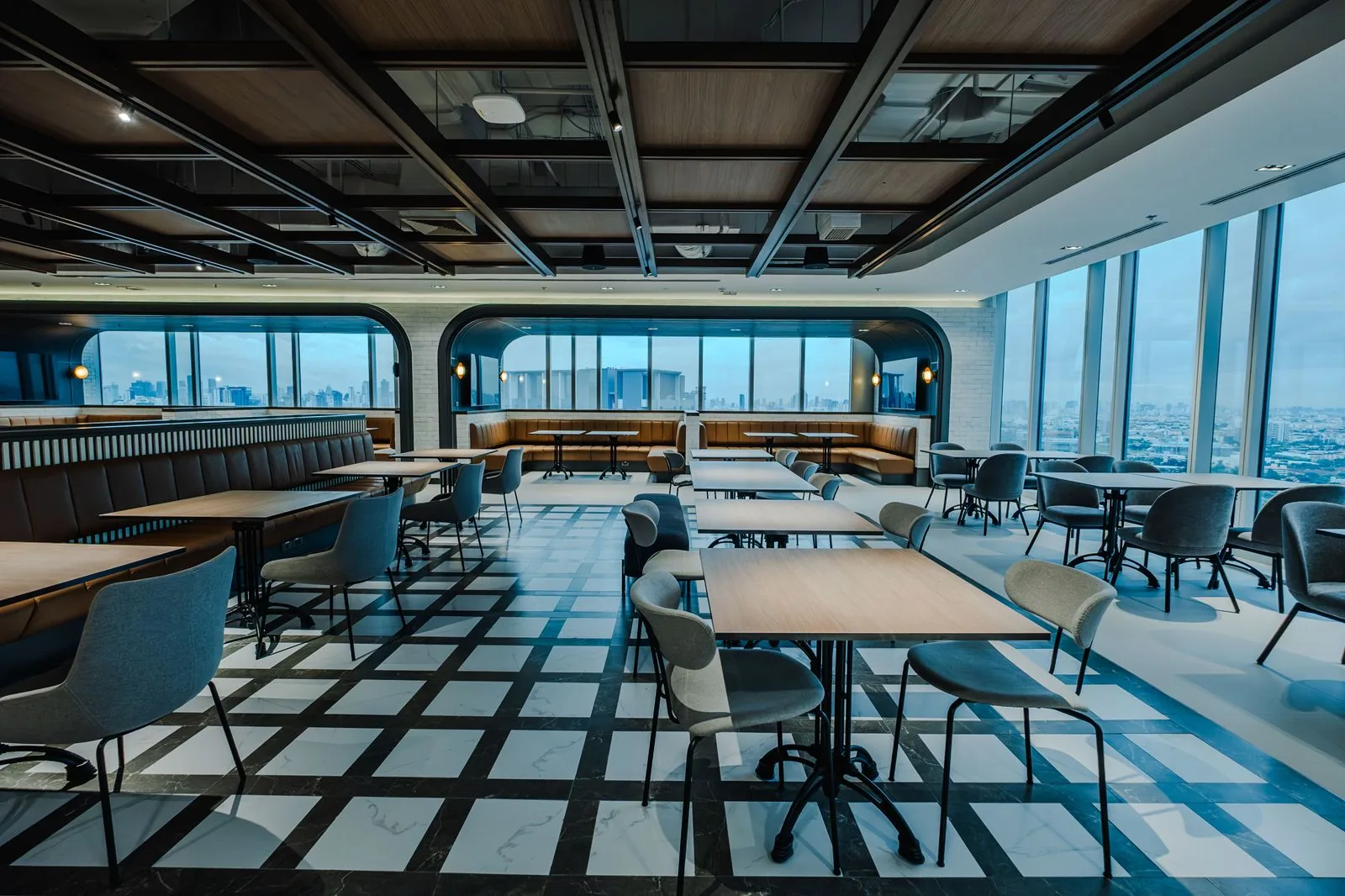 A rooftop restaurant dining room with checkered marble flooring and skyline views