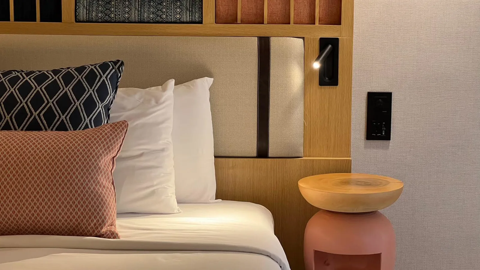Hotel guest room headboard detail with bedside pendant light and cushions