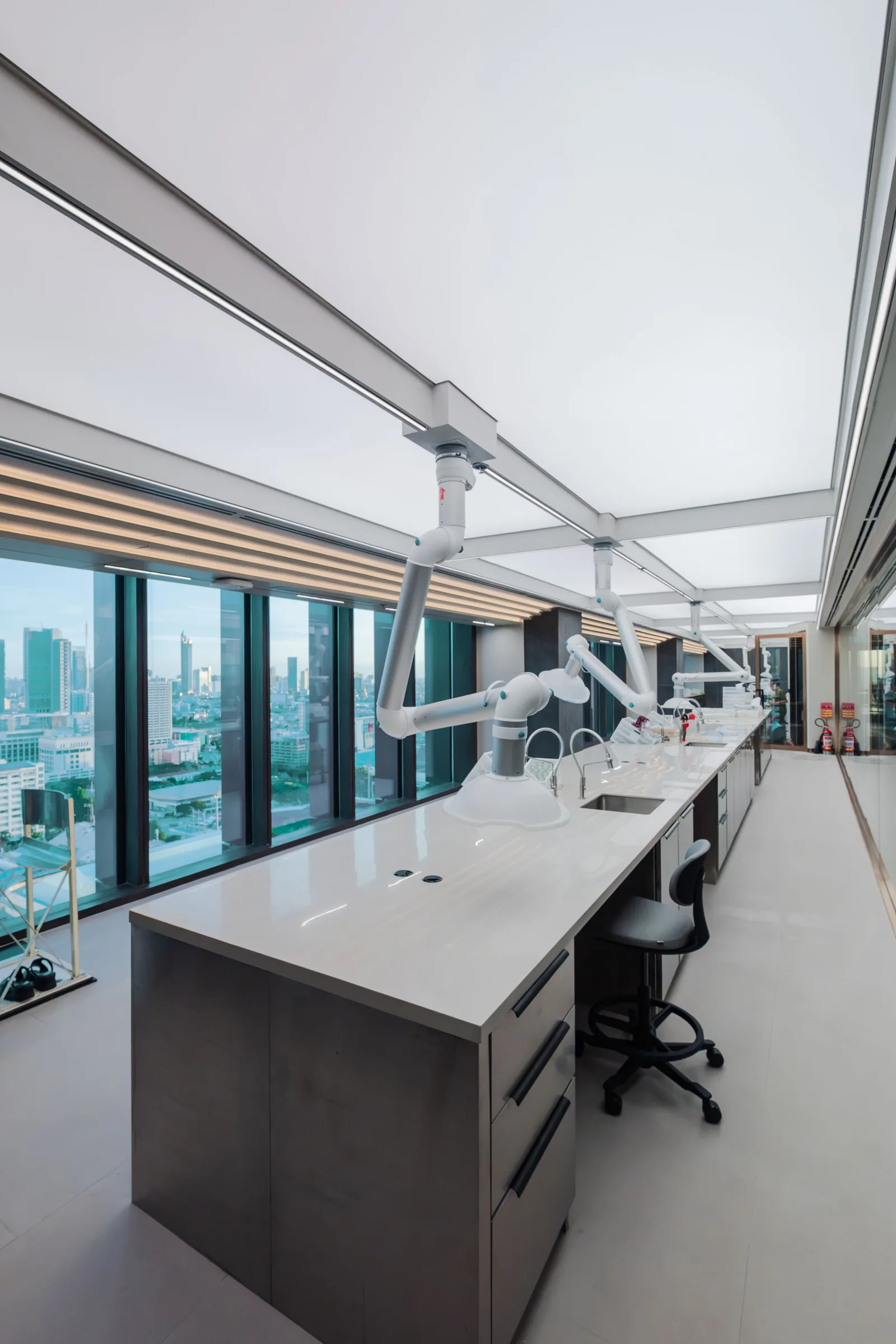 Laboratory bench with articulated arms and floor to ceiling city view glazing