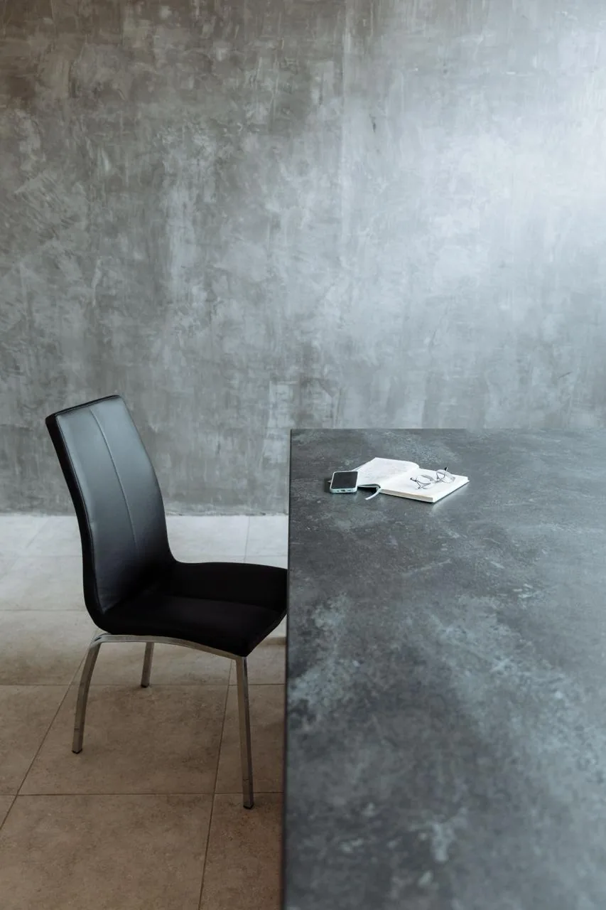 A quiet meeting corner with a notebook, glasses and phone laid out on a concrete table